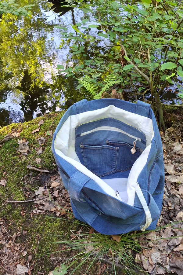 Innenansicht der Tasche aus alten Jeans genäht. Man sieht ein Reißverschlussfach und das helle Innenfutter.