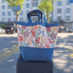 Schnittmuster „Carry & Go" – selbstgenähte Tasche mit Boden in Blau,auf Koffer stehend, mit floralem Blumenmuster und blauem Mittelteil